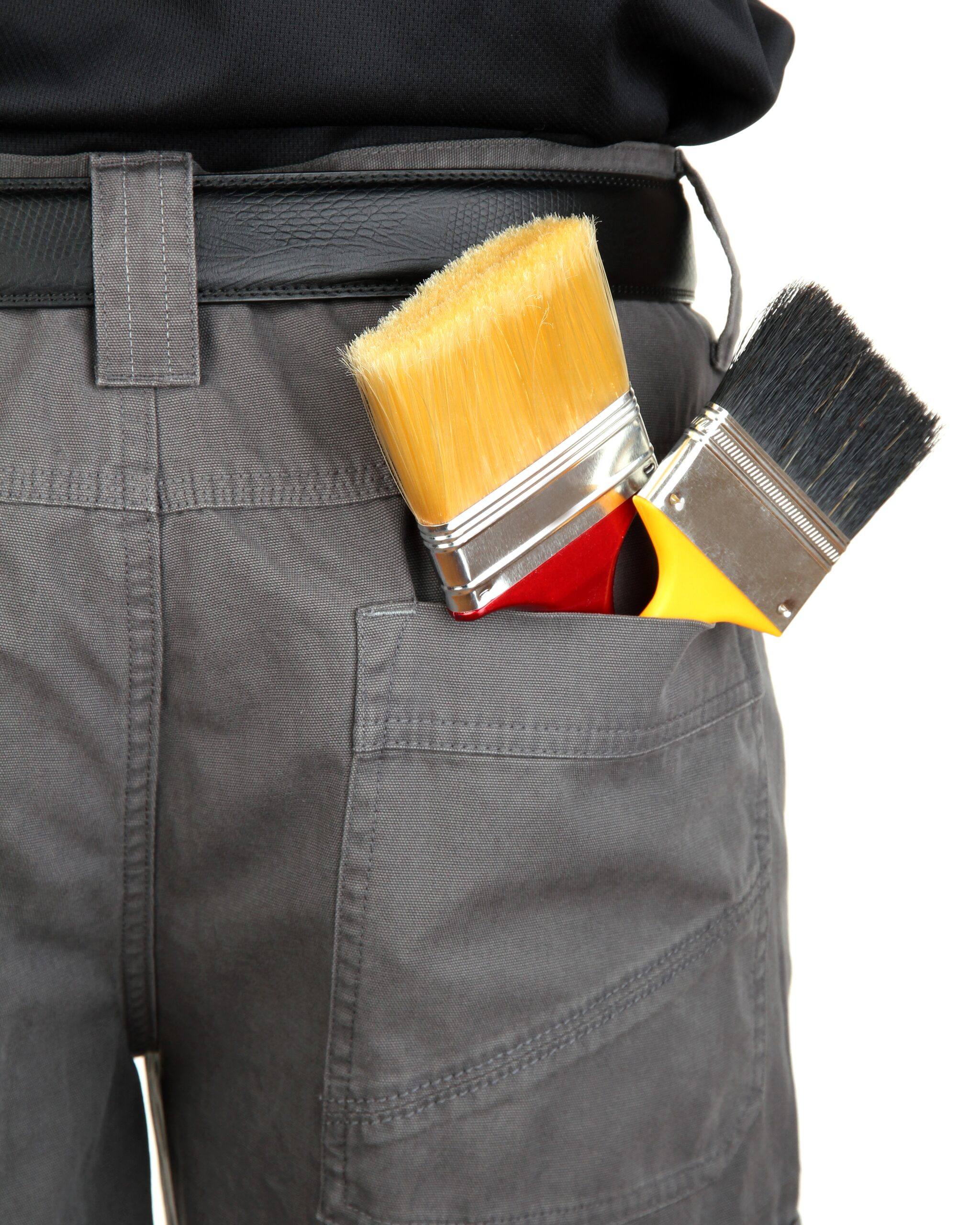 Brochas de pintor en el bolsillo trasero de un pantalón de trabajo