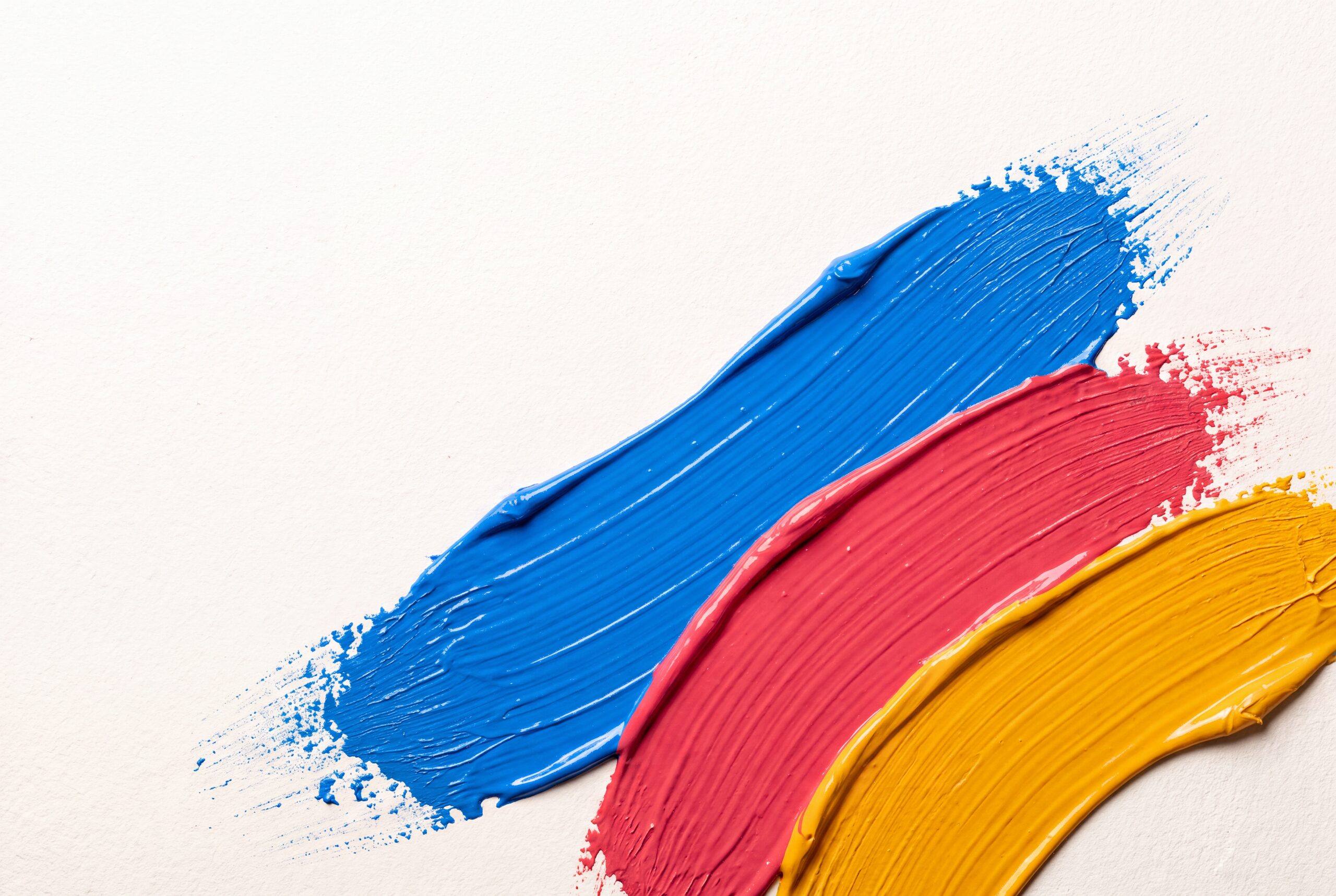 Tres pinceladas paralelas de pintura azul, magenta y ámbar sobre fondo blanco roto