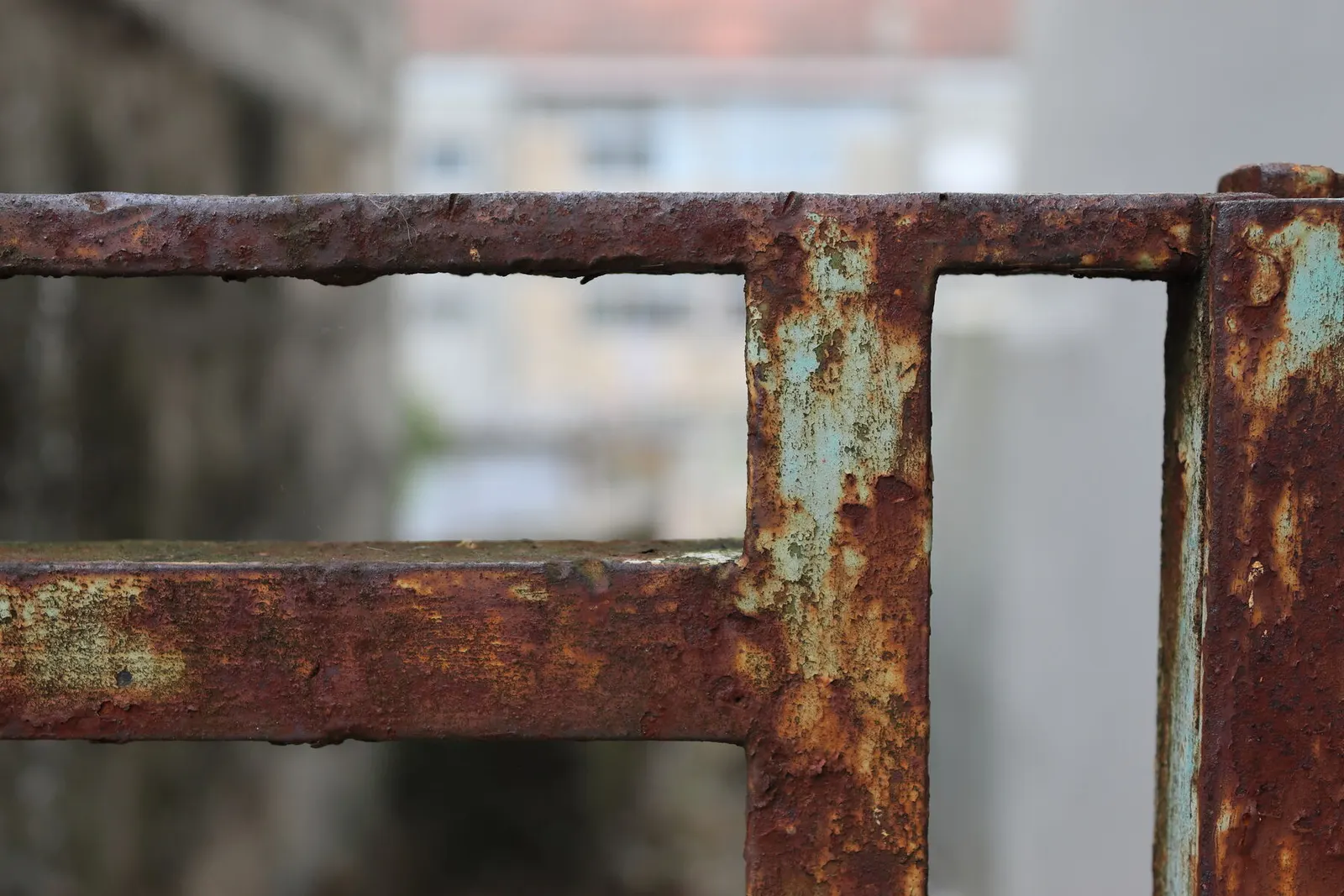 Reja de hierro de una ventana con zonas de óxido en los barrotes