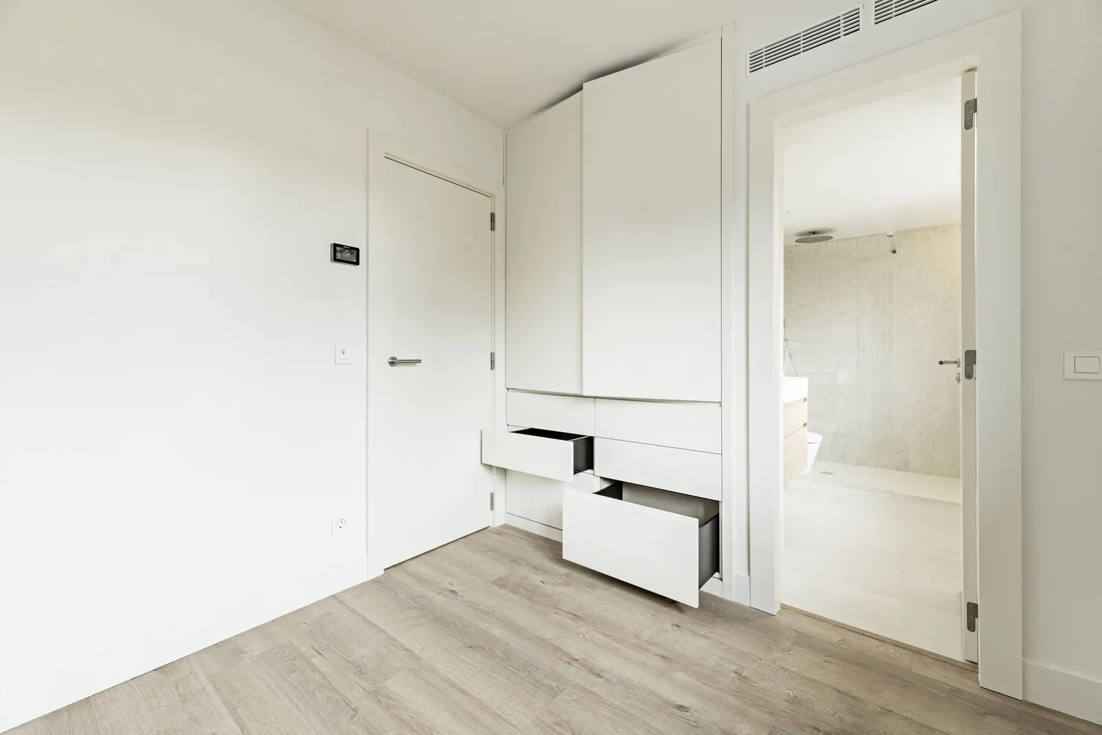 Dormitorio reformado con armario empotrado blanco de puertas lisas y cajones integrados