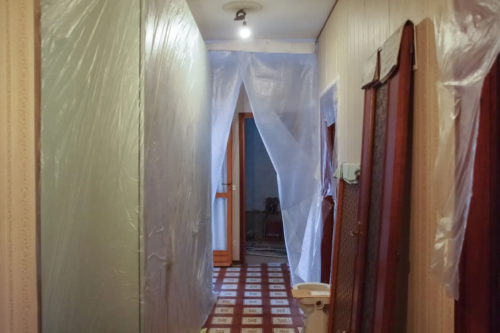 Pasillo con paredes y puertas cubiertas con plástico protector antes de pintar
