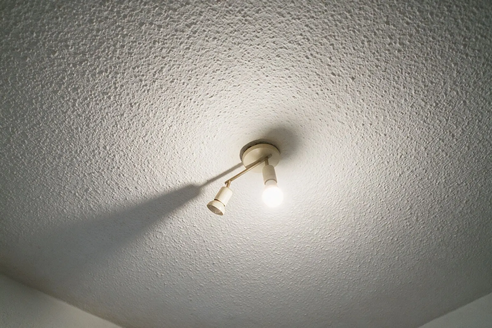 Techo con gotelé de un piso antiguo con una lámpara encendida que proyecta sombras sobre la textura
