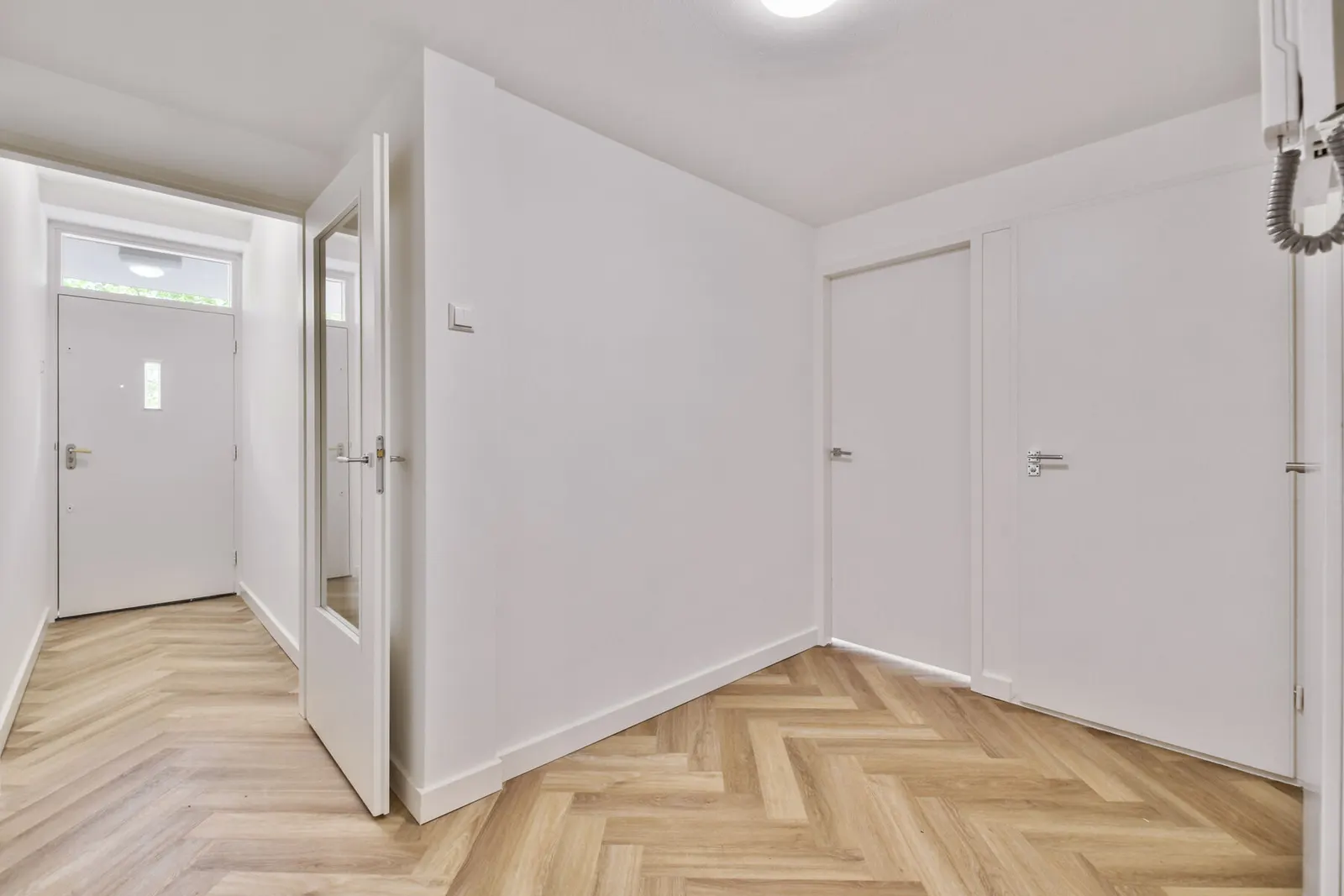 Habitación vacía con paredes lisas pintadas de blanco y suelo de madera clara