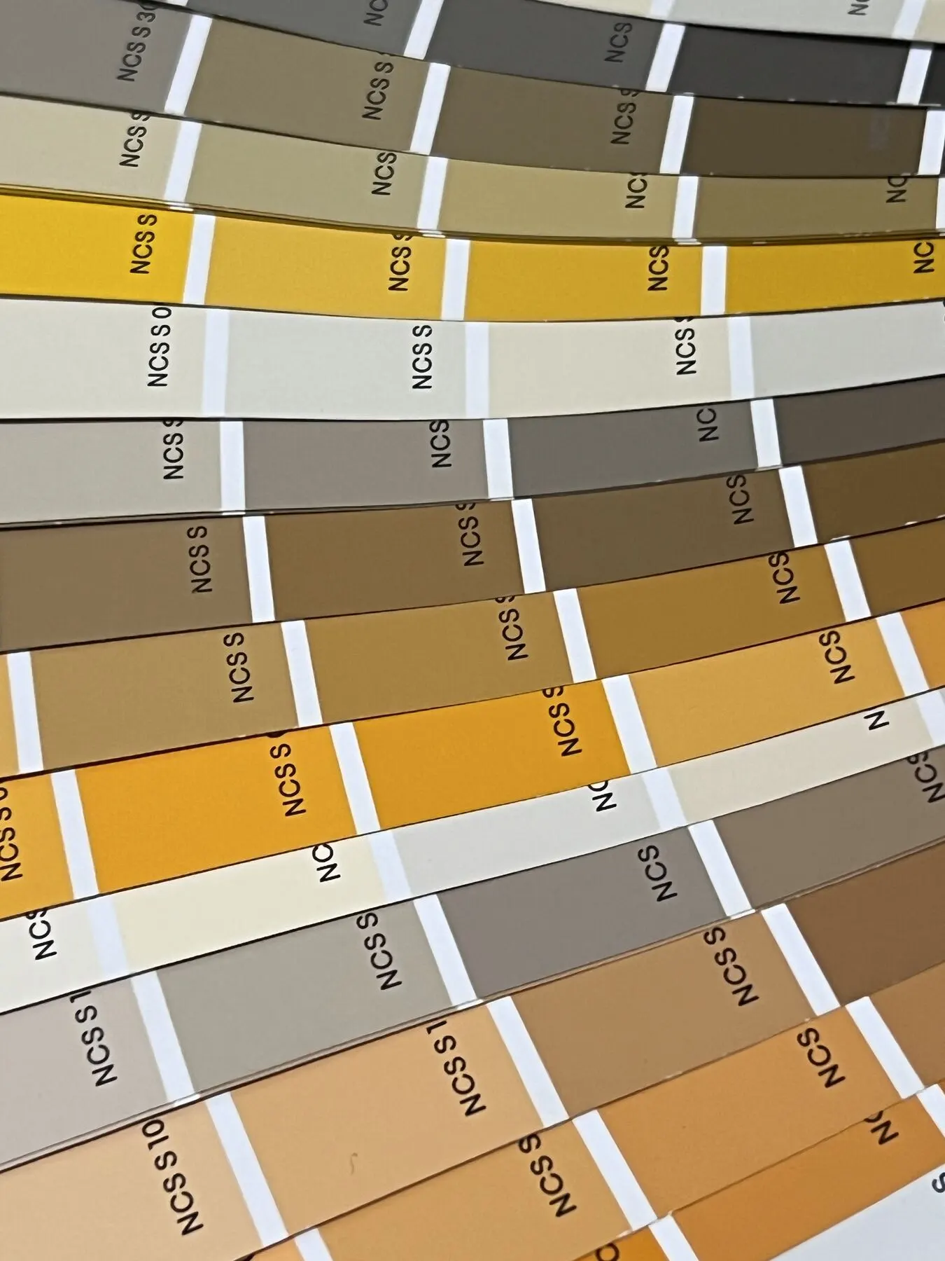 Abanico de cartas de colores en tonos ocre, gris y arena
