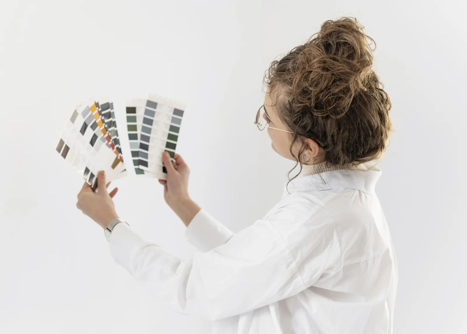 Mujer comparando un abanico de colores delante de una pared blanca